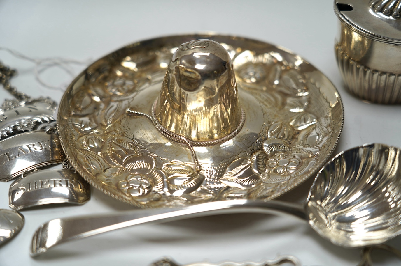 Four assorted 19th century silver wine labels, including a pair 'Sherry & Claret' by Joseph Wilmore, Birmingham, 1810, a Mexican 925 hat, a George III sauce ladle, by Eley & Fearn, London, 1802, a pair of silver sugar ni